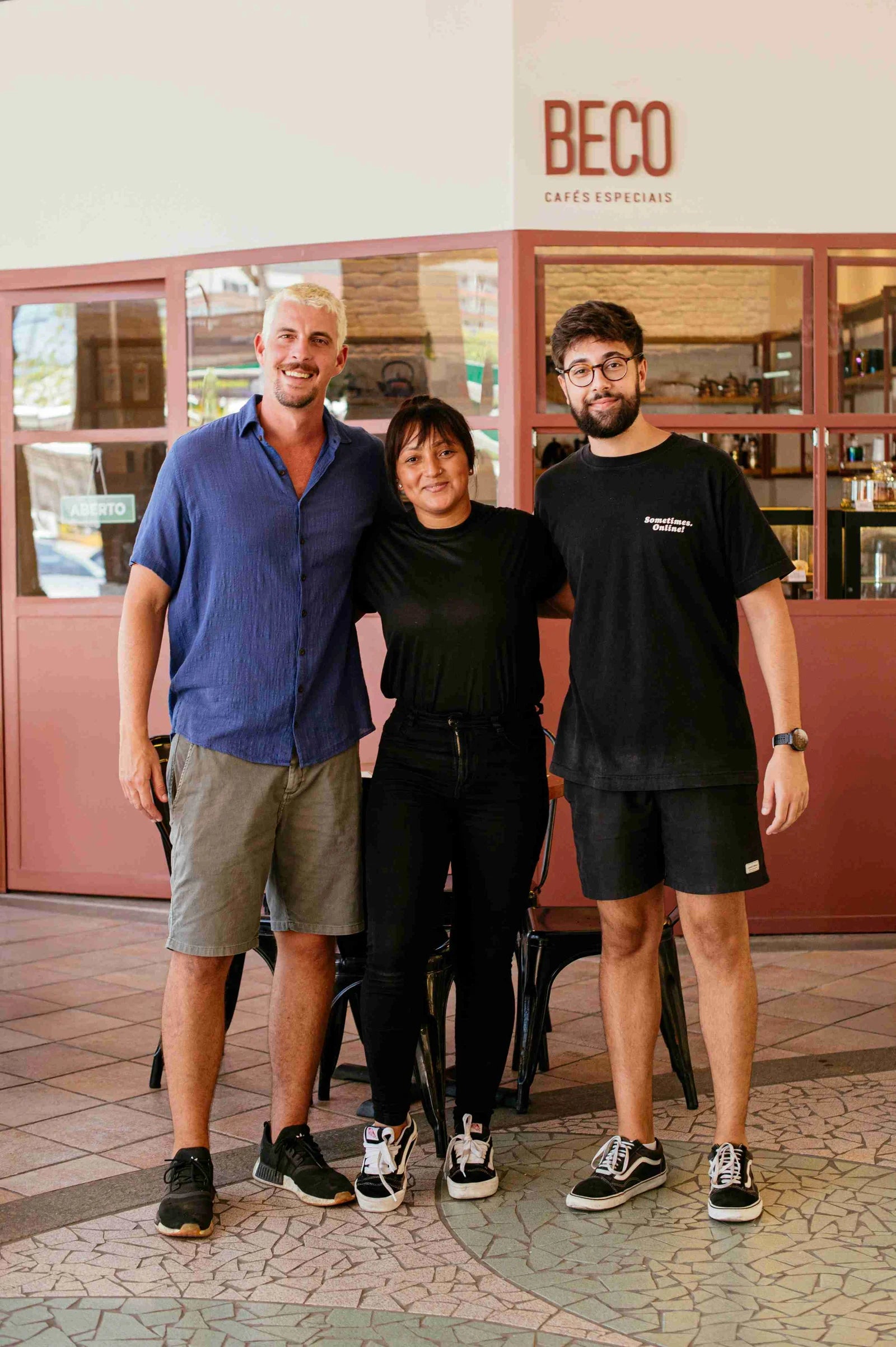 Equipe do Beco sorrindo em frente à cafeteria, com o letreiro BECO ao fundo