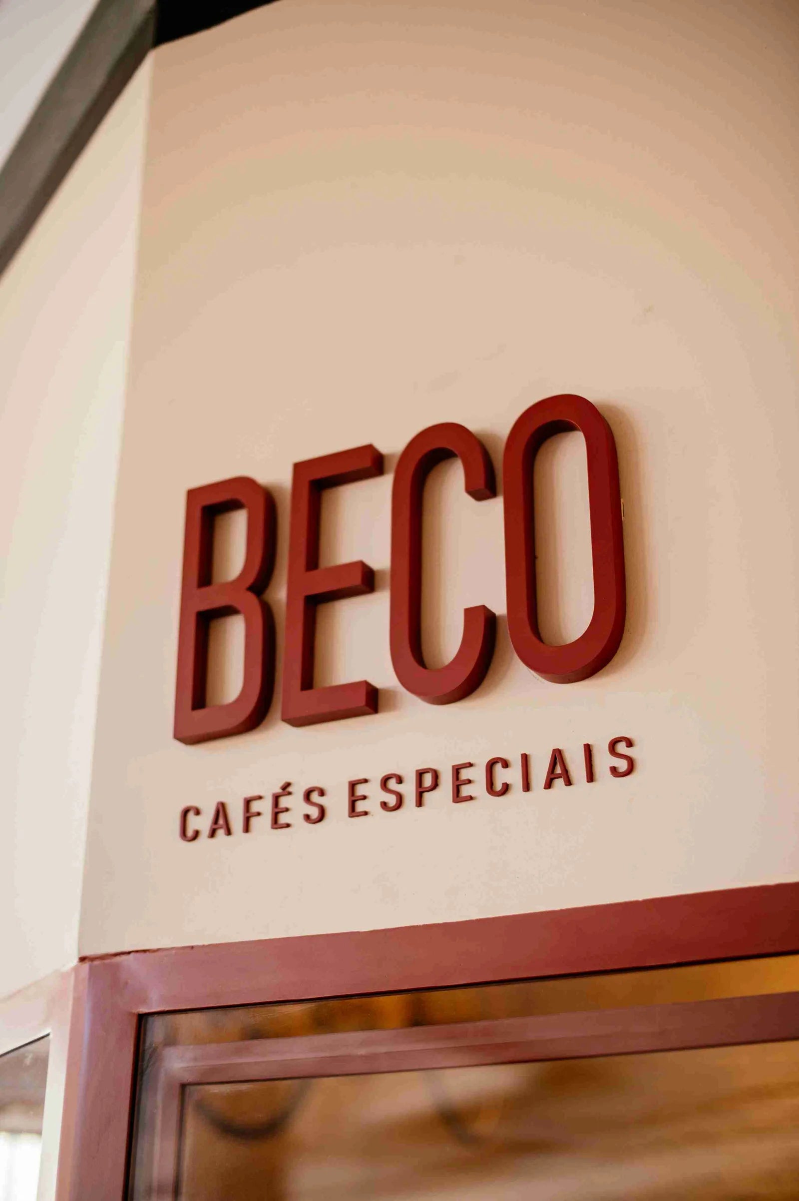 Fachada do Beco Cafés Especiais com letreiro em terracota sobre parede creme